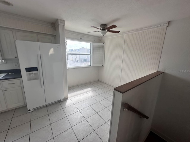 kitchen with light tile patterned floors, white fridge with ice dispenser, ceiling fan, and dark countertops