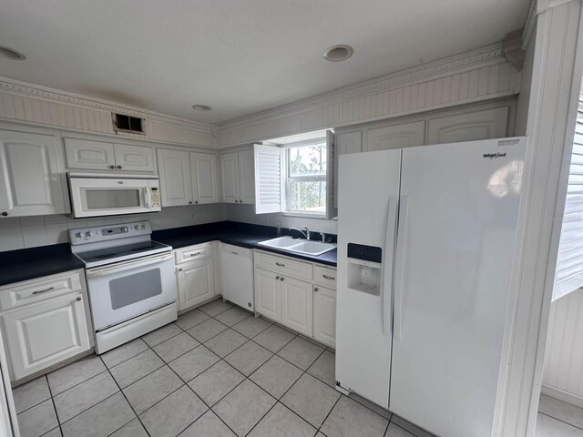 kitchen with dark countertops, white appliances, visible vents, and a sink