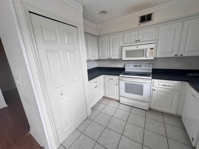 kitchen featuring white appliances, light tile patterned floors, visible vents, white cabinets, and dark countertops