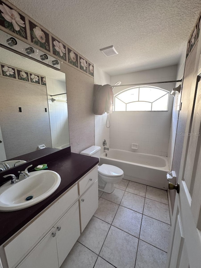 bathroom featuring tile patterned flooring, toilet, visible vents, vanity, and washtub / shower combination