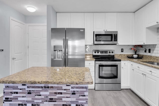 kitchen featuring light wood finished floors, tasteful backsplash, white cabinetry, and stainless steel appliances