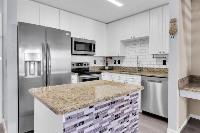 kitchen featuring light stone countertops, appliances with stainless steel finishes, white cabinets, and a sink