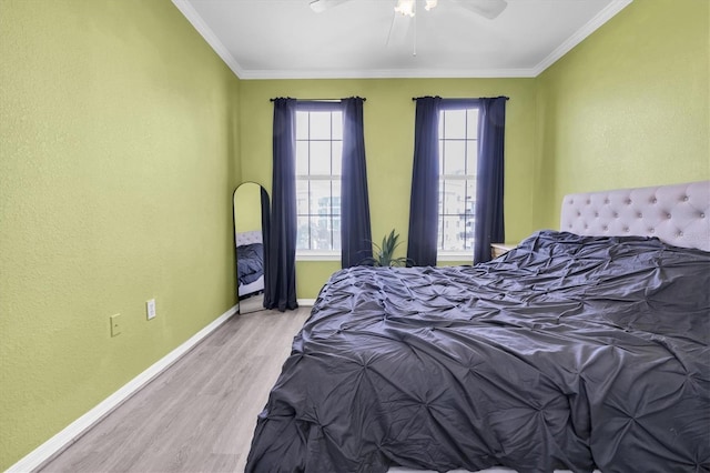 bedroom featuring light wood finished floors, ceiling fan, baseboards, and crown molding