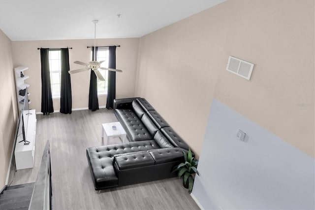 living area featuring a ceiling fan, baseboards, visible vents, and wood finished floors