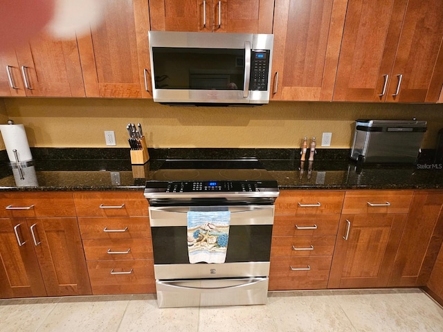 530 Sandy Hook Rd, Treasure Island, FL 33706 - kitchen with stainless steel appliances, brown cabinetry, and dark stone counters