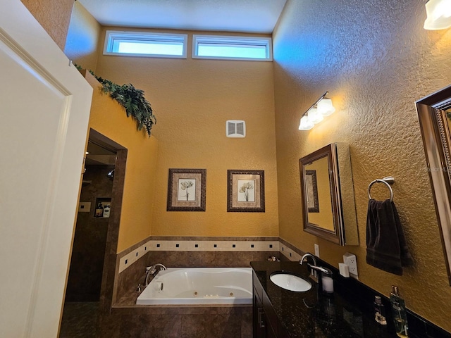 530 Sandy Hook Rd, Treasure Island, FL 33706 - bathroom featuring a towering ceiling, vanity, a textured wall, visible vents, and a tub with jets