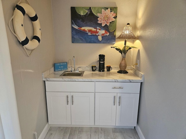 530 Sandy Hook Rd, Treasure Island, FL 33706 - bar with light wood-style floors, wet bar, a sink, and baseboards