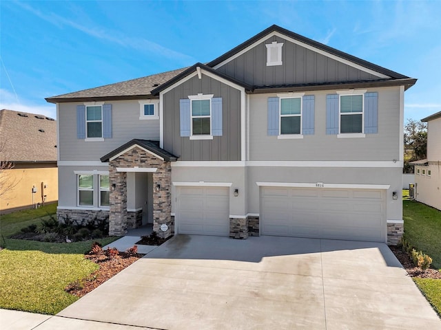 craftsman house featuring concrete driveway, an attached garage, board and batten siding, a front yard, and stone siding