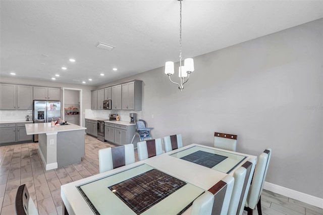 dining space with light wood-type flooring, baseboards, a notable chandelier, and recessed lighting