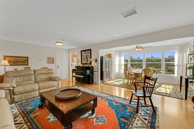 living room with visible vents, ceiling fan, and light wood finished floors