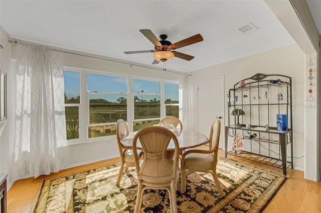 dining space with a ceiling fan, visible vents, and wood finished floors