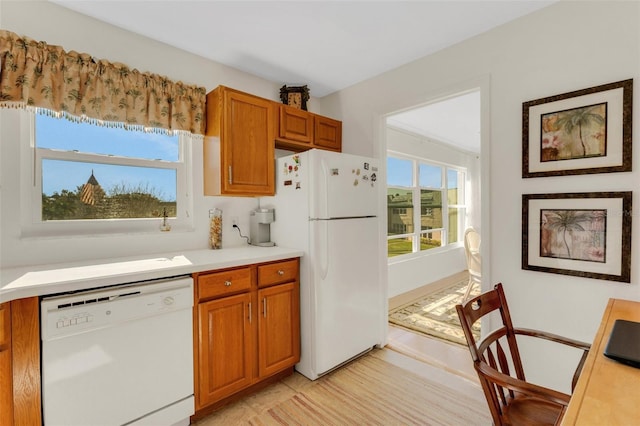 kitchen featuring brown cabinets, white appliances, and light countertops