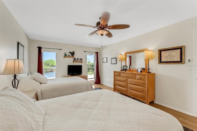 bedroom featuring access to exterior, ceiling fan, baseboards, and wood finished floors