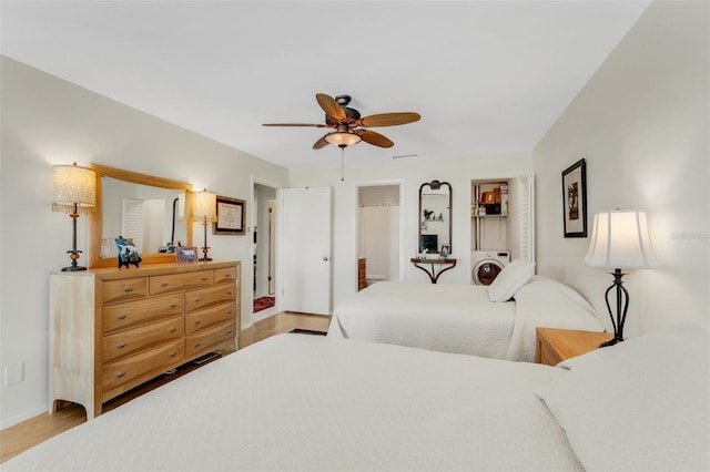 bedroom featuring a ceiling fan, baseboards, washer / clothes dryer, and wood finished floors