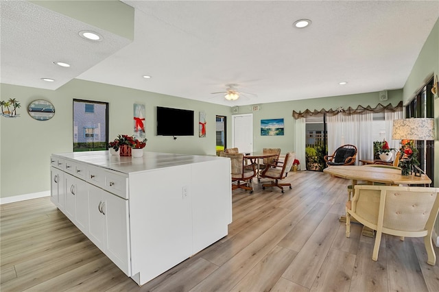 kitchen with light wood-style flooring, recessed lighting, a ceiling fan, white cabinets, and a center island