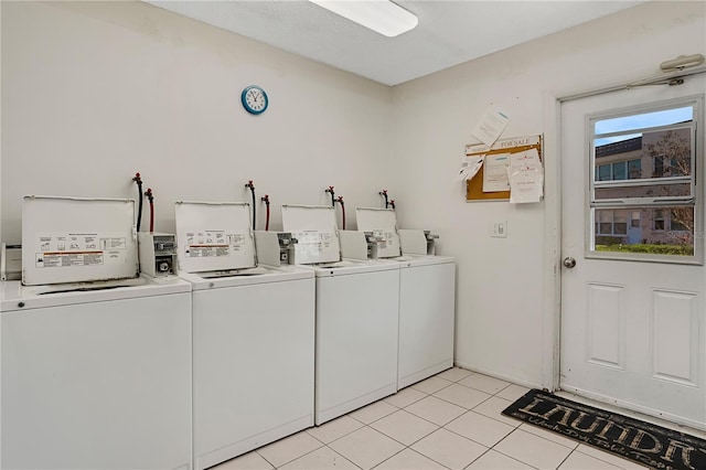 common laundry area with washer and dryer and light tile patterned flooring