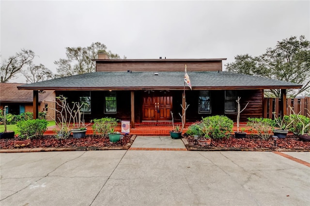 view of front of property with a chimney, a porch, and roof with shingles