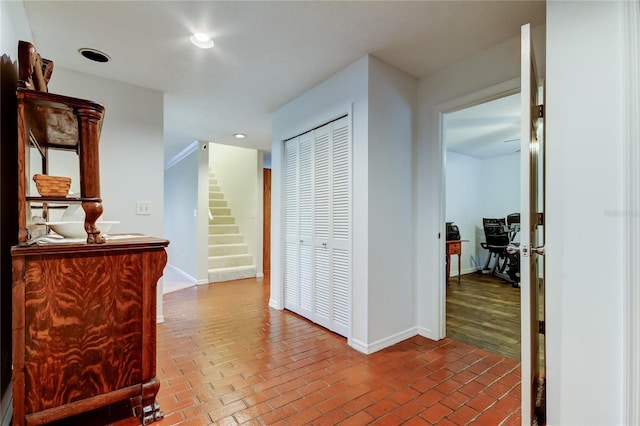 hallway featuring brick floor, stairs, baseboards, and recessed lighting