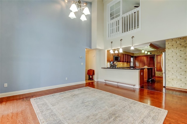 living room with a baseboard heating unit, wood finished floors, and baseboards