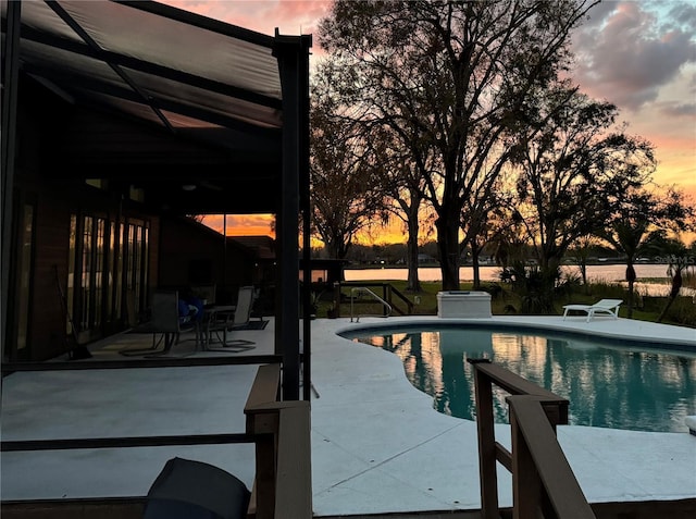 pool at dusk featuring an outdoor pool and a patio