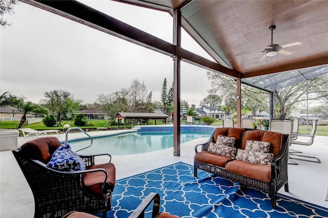 outdoor pool with a patio area, glass enclosure, and ceiling fan