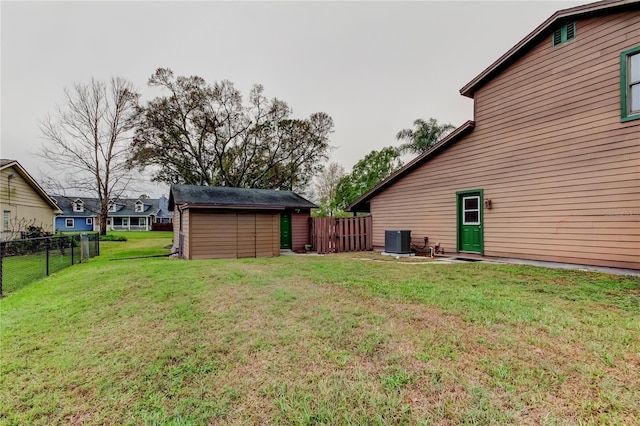 view of yard with an outbuilding, a fenced backyard, a storage unit, and central AC unit