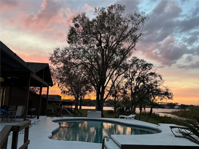 pool at dusk with a patio area and an outdoor pool