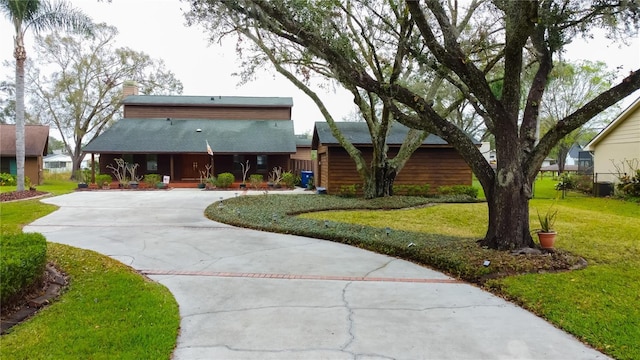 view of front of home with driveway, a front lawn, and a chimney