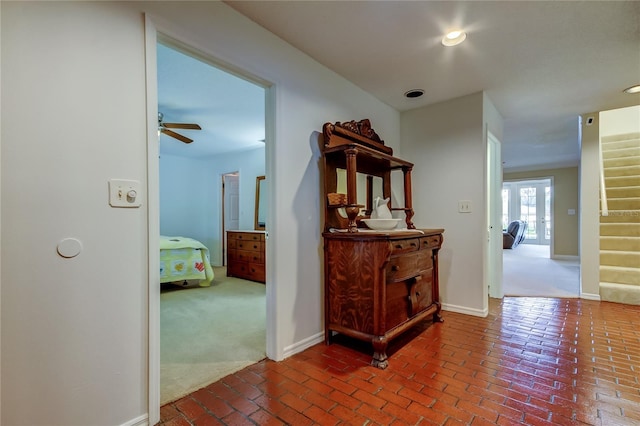 corridor with stairs, brick floor, carpet flooring, and baseboards