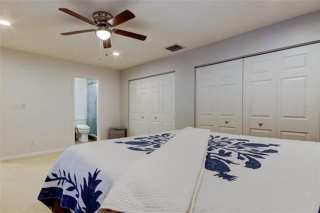 bedroom featuring baseboards, visible vents, ensuite bath, carpet, and two closets