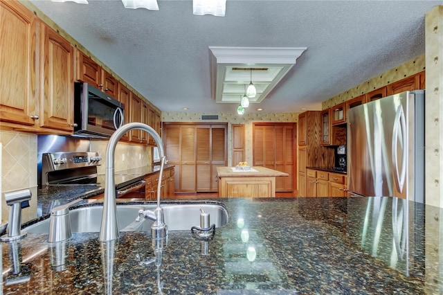 kitchen with decorative backsplash, appliances with stainless steel finishes, dark stone countertops, a textured ceiling, and a sink