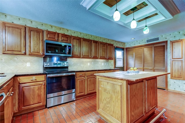 kitchen featuring brick floor, visible vents, hanging light fixtures, appliances with stainless steel finishes, and wallpapered walls