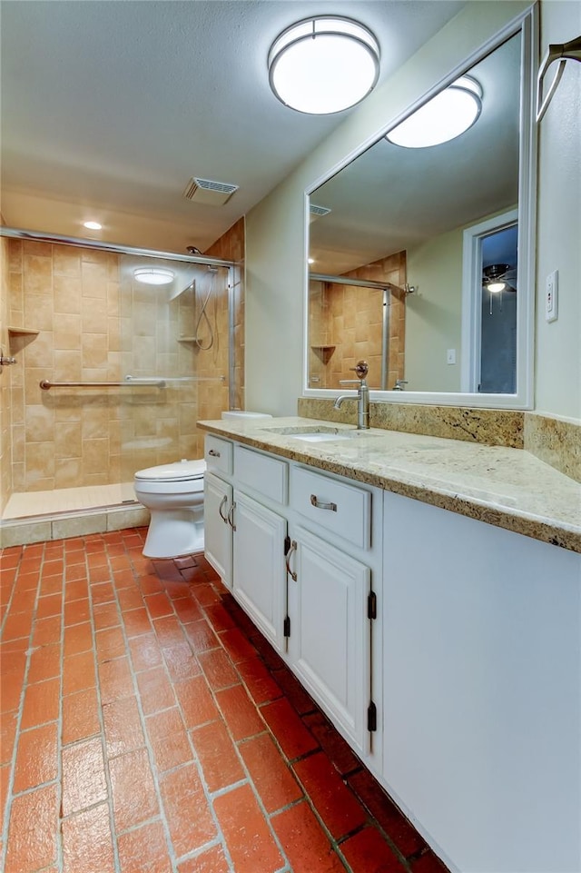 bathroom with toilet, vanity, a tile shower, and visible vents