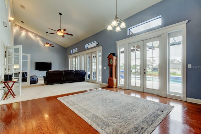 living area with baseboards, visible vents, wood finished floors, french doors, and high vaulted ceiling