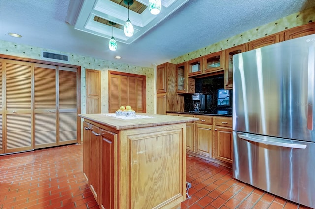 kitchen featuring wallpapered walls, visible vents, glass insert cabinets, freestanding refrigerator, and brick floor