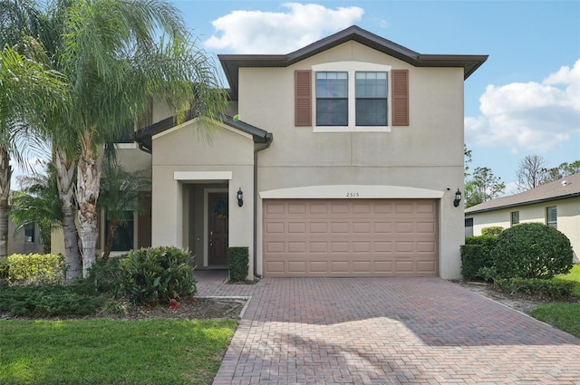 traditional-style home featuring decorative driveway, an attached garage, and stucco siding