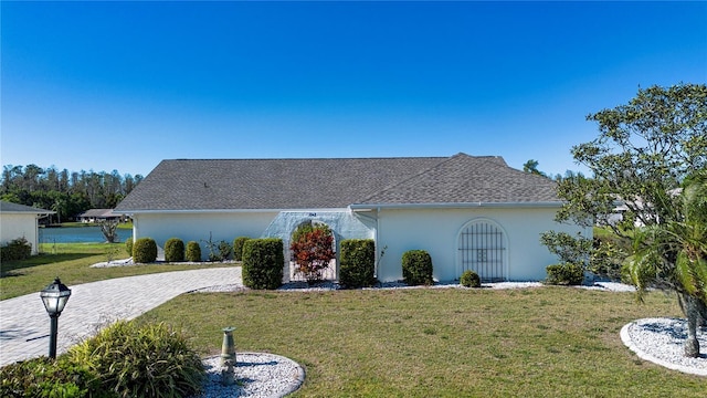 view of front of home featuring a front yard, decorative driveway, roof with shingles, and stucco siding