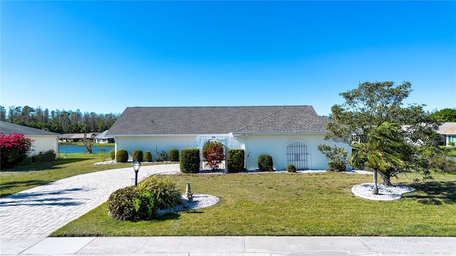 view of front of home featuring stucco siding, decorative driveway, and a front yard