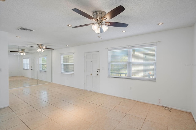 empty room featuring a textured ceiling and light tile patterned floors