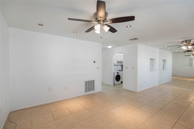 spare room featuring ceiling fan, light tile patterned floors, washer / clothes dryer, and a textured ceiling