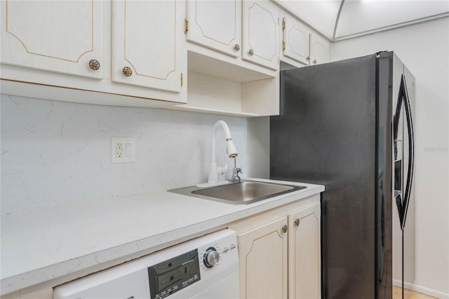 kitchen featuring sink, dishwasher, tasteful backsplash, and black fridge with ice dispenser