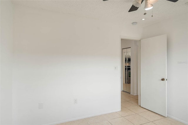 tiled empty room with a textured ceiling and ceiling fan