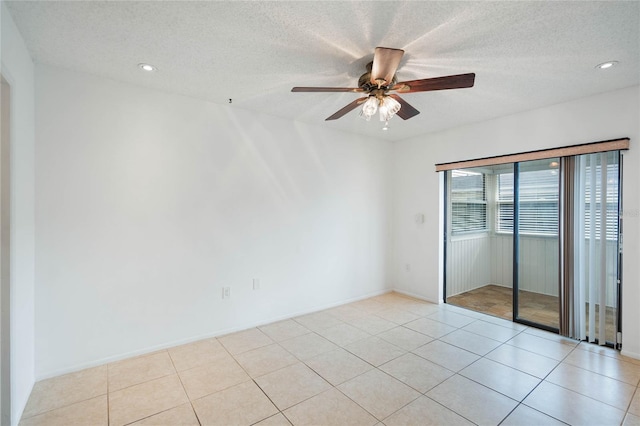 tiled empty room featuring ceiling fan and a textured ceiling