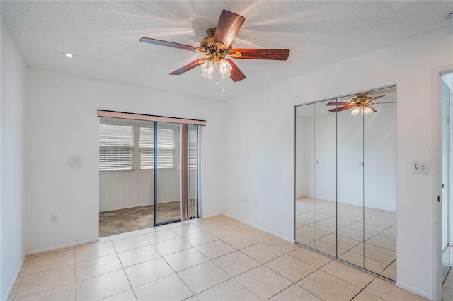 unfurnished bedroom featuring ceiling fan, light tile patterned floors, a textured ceiling, and a closet