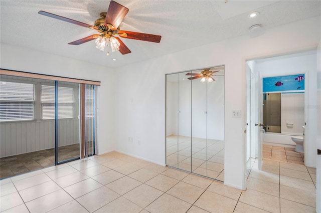 unfurnished bedroom with a textured ceiling, a closet, ceiling fan, and light tile patterned floors