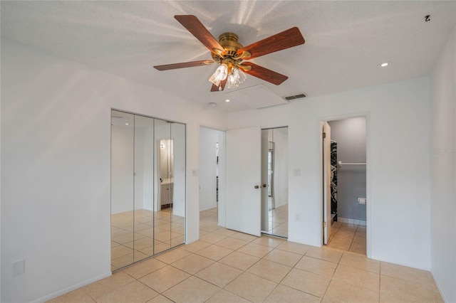 unfurnished bedroom featuring a textured ceiling, light tile patterned flooring, ceiling fan, and ensuite bath