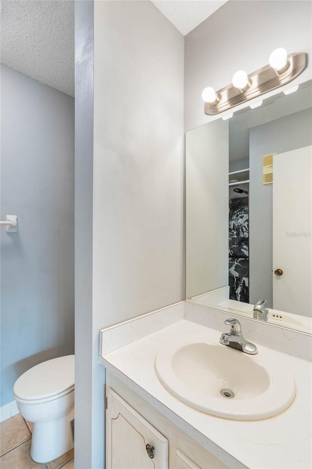 bathroom with toilet, a textured ceiling, walk in shower, tile patterned floors, and vanity