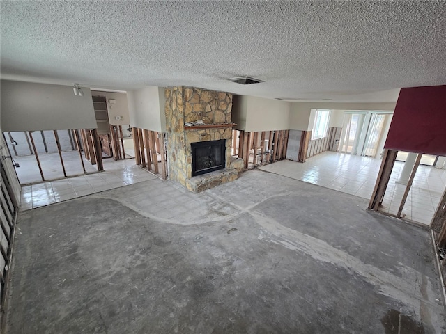 unfurnished living room featuring concrete flooring, a textured ceiling, and a fireplace