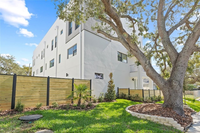 view of side of home featuring a yard, fence, and stucco siding