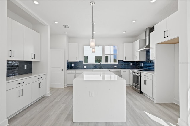 307 15th St N, Saint Petersburg, FL 33705 - kitchen with appliances with stainless steel finishes, white cabinets, light wood-style floors, and wall chimney range hood